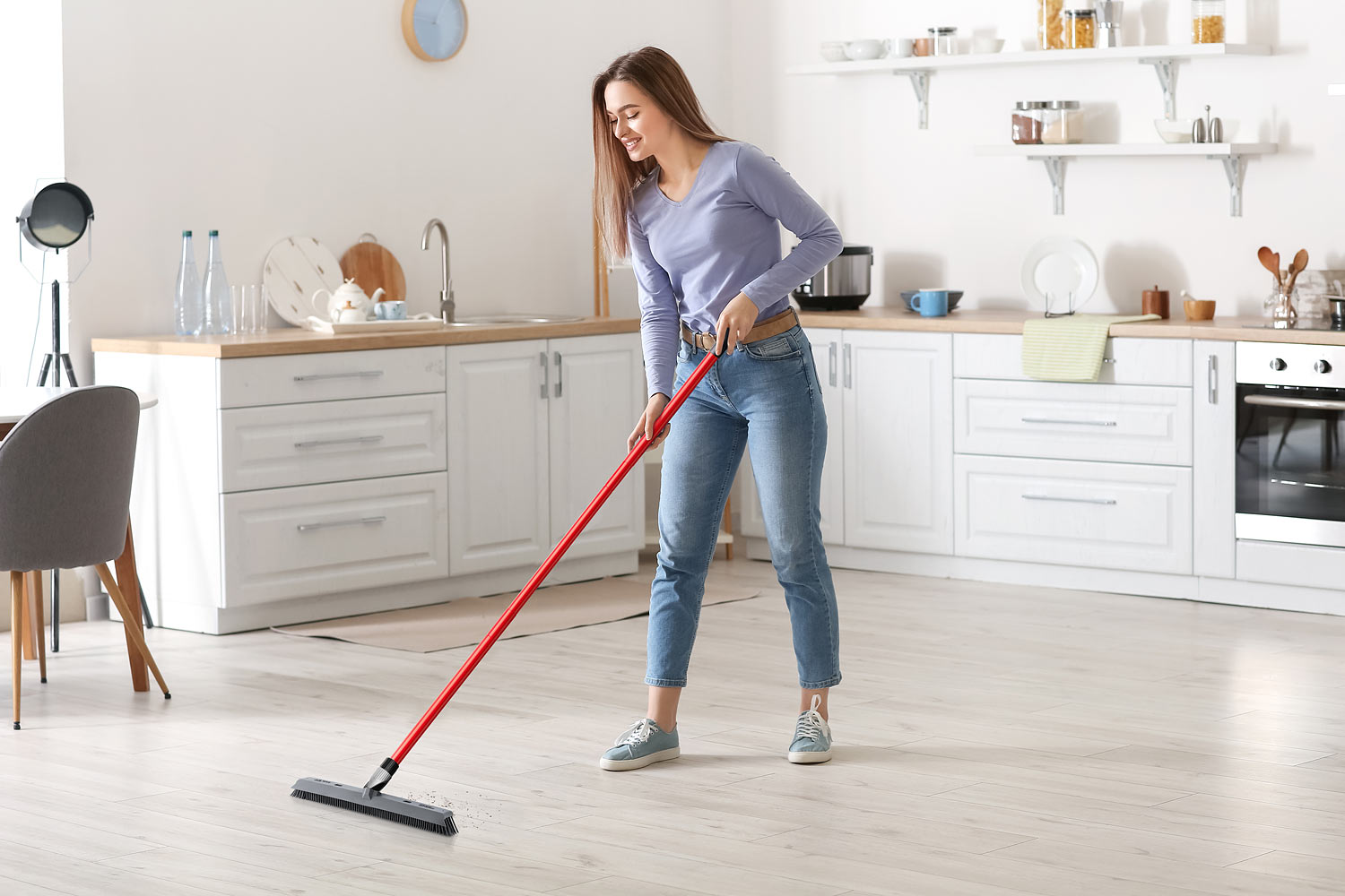 lifestyle image of a woman cleaning a floor with a brush